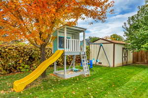 View of playground with a shed and a lawn