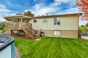 Back of house featuring central air condition unit, a deck, and a lawn