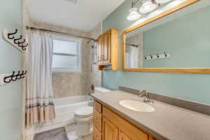 Full bathroom with vanity, shower / tub combo with curtain, toilet, and tile patterned floors