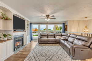 Living room featuring built in shelves, a textured ceiling, light hardwood / wood-style flooring, and a fireplace