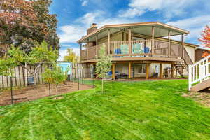 Rear view of house with a deck and a lawn