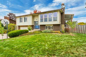 Split foyer home featuring a garage and a front lawn