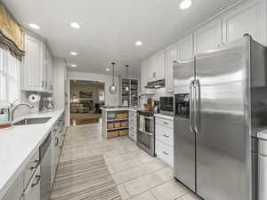 Kitchen with appliances with stainless steel finishes, sink, hanging light fixtures, white cabinetry, and decorative backsplash