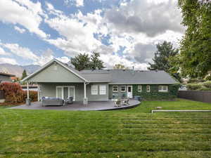 Back of house with a mountain view, a patio area, and a lawn