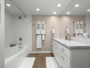 Bathroom with vanity, tiled shower / bath combo, and wood-type flooring