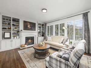 Living room featuring built in shelves and dark hardwood / wood-style flooring