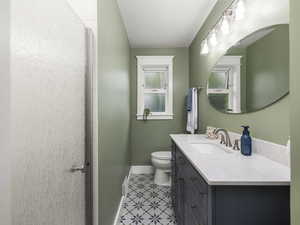 Bathroom featuring toilet, an enclosed shower, vanity, and tile patterned flooring