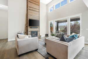 Living room with a towering ceiling, a large fireplace, and light wood-type flooring