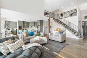 Living room featuring light hardwood / wood-style floors, sink, and a towering ceiling