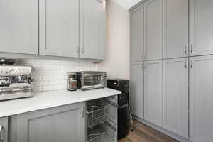 Kitchen with gray cabinetry, tasteful backsplash, and dark wood-type flooring