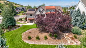 Exterior space with a mountain view, solar panels, a front lawn, and a garage