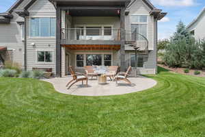 Rear view of property featuring a patio area, a yard, and a balcony