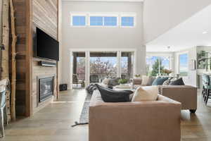 Living room featuring light hardwood / wood-style floors, a high ceiling, plenty of natural light, and a fireplace