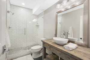 Bathroom featuring toilet, vanity, and a shower with door