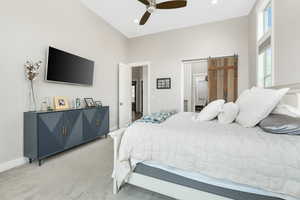 Carpeted bedroom featuring ceiling fan and a barn door