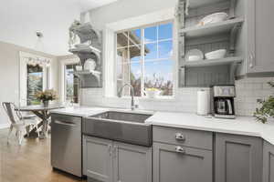 Kitchen featuring hanging light fixtures, gray cabinets, dishwasher, light hardwood / wood-style floors, and sink