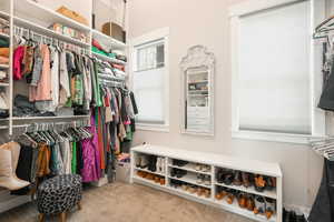 Walk in closet featuring light colored carpet