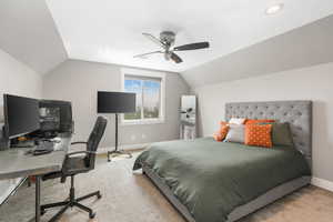 Carpeted bedroom with lofted ceiling and ceiling fan