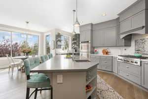 Kitchen with light hardwood / wood-style floors, sink, a center island with sink, and a kitchen bar