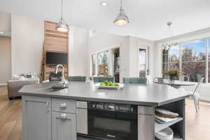 Kitchen with light wood-type flooring, sink, plenty of natural light, and a kitchen island with sink