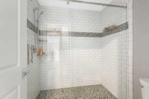 Bathroom featuring a tile shower and toilet