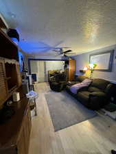 Living room featuring light hardwood / wood-style floors, a textured ceiling, and ceiling fan