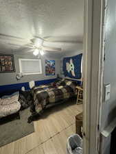 Bedroom featuring a textured ceiling, wood-type flooring, and ceiling fan