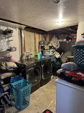 Washroom with a textured ceiling and washer and clothes dryer