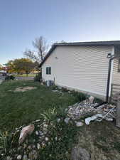 View of side of property featuring cooling unit and a lawn