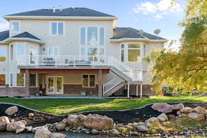 Back of house featuring french doors, a patio, a deck, and a yard