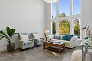 Living room featuring a towering ceiling, a notable chandelier, and wood-type flooring