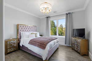 upstairs bedroom #2 featuring wood-type flooring, ornamental molding, and a chandelier