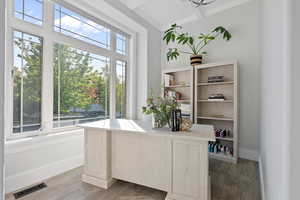 Home office with ornamental molding and light hardwood / wood-style flooring