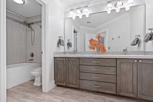 upstairs full bathroom with toilet, wood-type flooring, tiled shower / bath, crown molding, and vanity