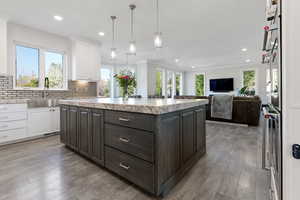 Kitchen with a kitchen island, white cabinets, dark brown cabinetry, and a healthy amount of sunlight