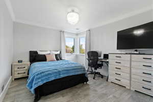 upstairs bedroom #4 with light hardwood / wood-style floors and ornamental molding