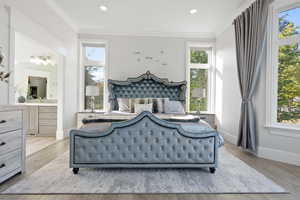 main floor primary ensuite bathroom, ornamental molding, and light hardwood / wood-style flooring