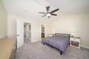 Primary bedroom with ceiling fan, ensuite bath, lofted ceiling, and light colored carpet