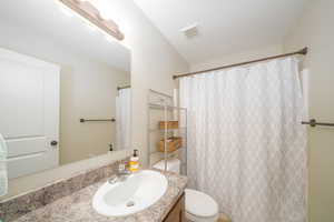 Bathroom featuring toilet, vanity, and a shower with shower curtain