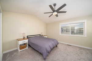 Carpeted primary bedroom featuring vaulted ceiling and ceiling fan