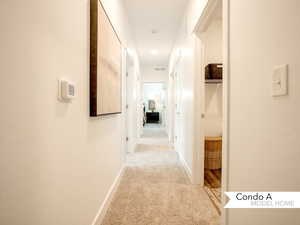 Hallway featuring light colored carpet