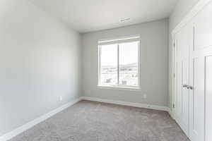 Unfurnished bedroom featuring baseboards, a textured ceiling, visible vents, and carpet