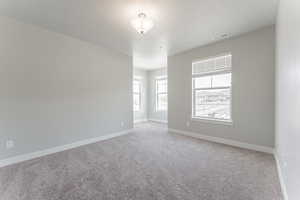 Unfurnished room featuring baseboards, visible vents, and light colored carpet