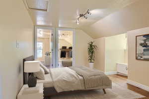 Bedroom with vaulted ceiling, a textured ceiling, and light wood-type flooring