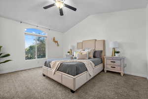 Carpeted bedroom featuring ceiling fan and vaulted ceiling