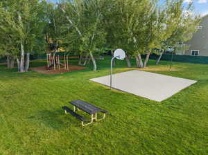 View of basketball court featuring a lawn and a playground