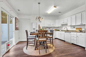 Kitchen with white appliances, pendant lighting, dark hardwood / wood-style floors, and white cabinets