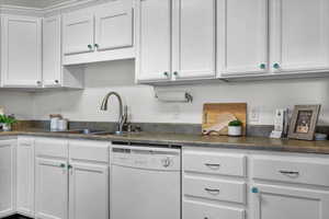 Kitchen featuring white cabinetry, sink, and white dishwasher