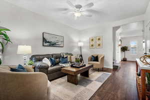 Living room featuring dark wood-type flooring and ceiling fan