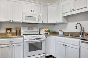 Kitchen with sink, white cabinets, and white appliances